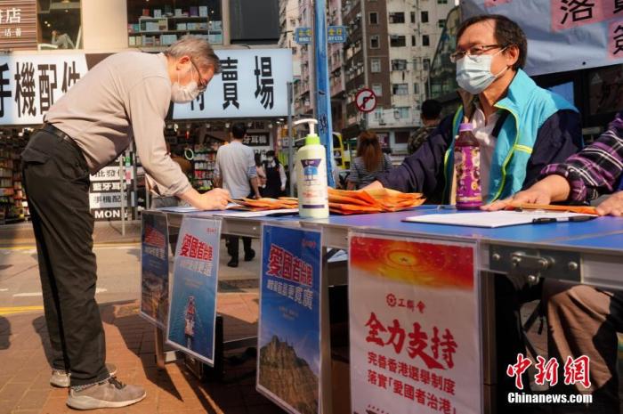 资料图：3月9日，香港市民纷纷停下脚步，签名支持完善香港选举制度，落实“爱国者治港”。
中新社记者 张炜 摄