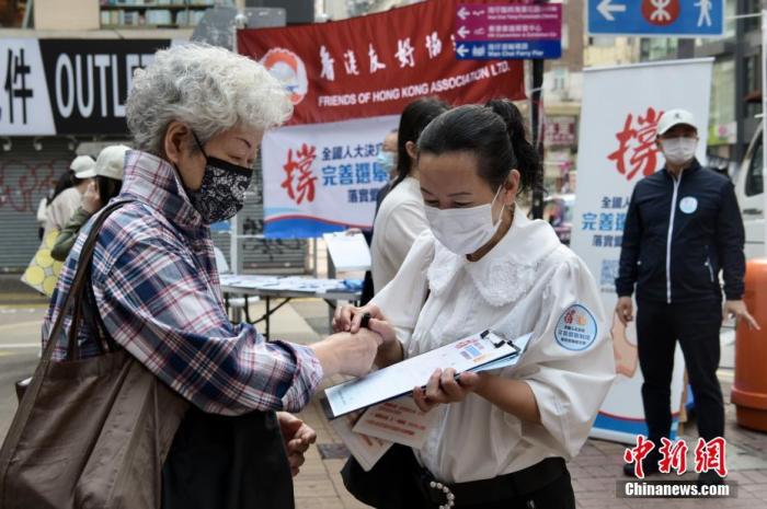 资料图：3月12日上午，香港市民到湾仔街站签名支持完善香港选举制度，落实“爱国者治港”。图为市民签名支持。
中新社记者 李志华 摄