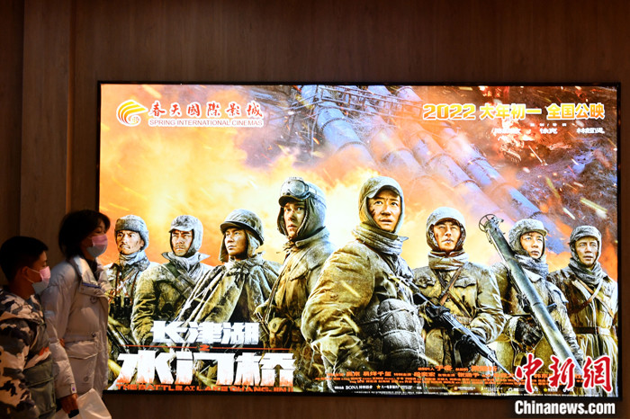 资料图为2月1日大年初一，市民走向福州一影院时经过《长津湖之水门桥》电影宣传海报。 中新社记者 吕明 摄